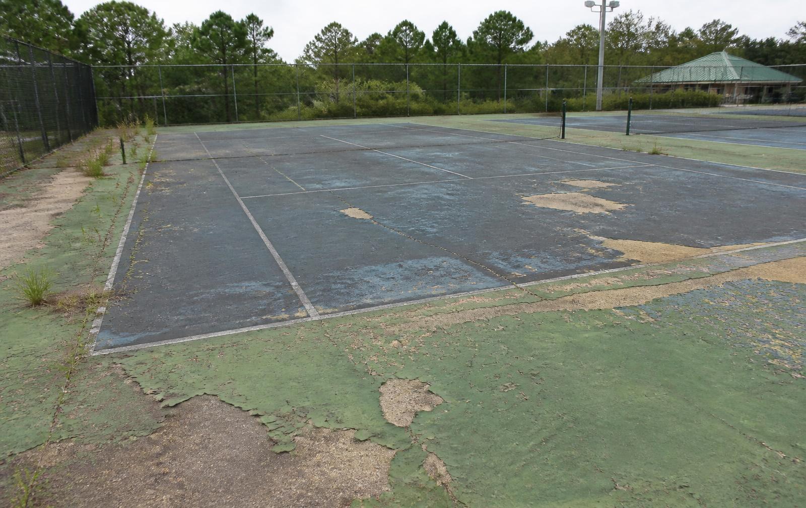 Worn and faded tennis court surface before resurfacing